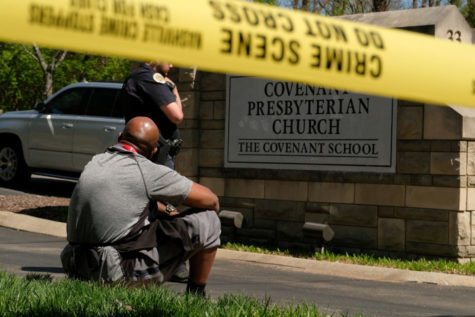 Mario Dennis, one of the kitchen staff at the Covenant School, sits near a police officer after a shooting at the facility in Nashville, Tennessee on March 27, 2023.  